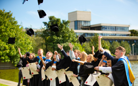 New UCD graduates throwing caps into the air at their graduation by the main UCD lake.